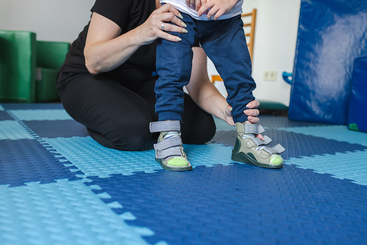 Young boy receives supportive assistance during a physical rehabilitation session aimed at improving mobility and strength